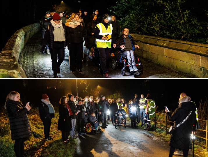 Groups of guests at the Castlemilk Park launch event walk and wheel along a path now lit by newly installed lighting, during a celebration event.